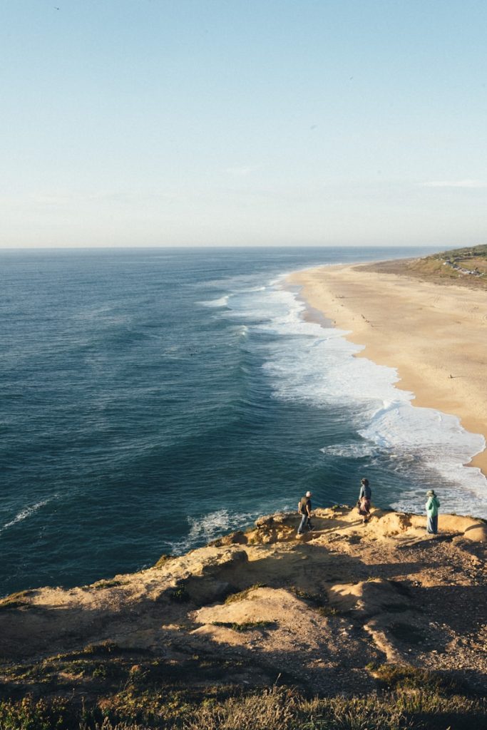 a group of people standing on top of a cliff next to the ocean